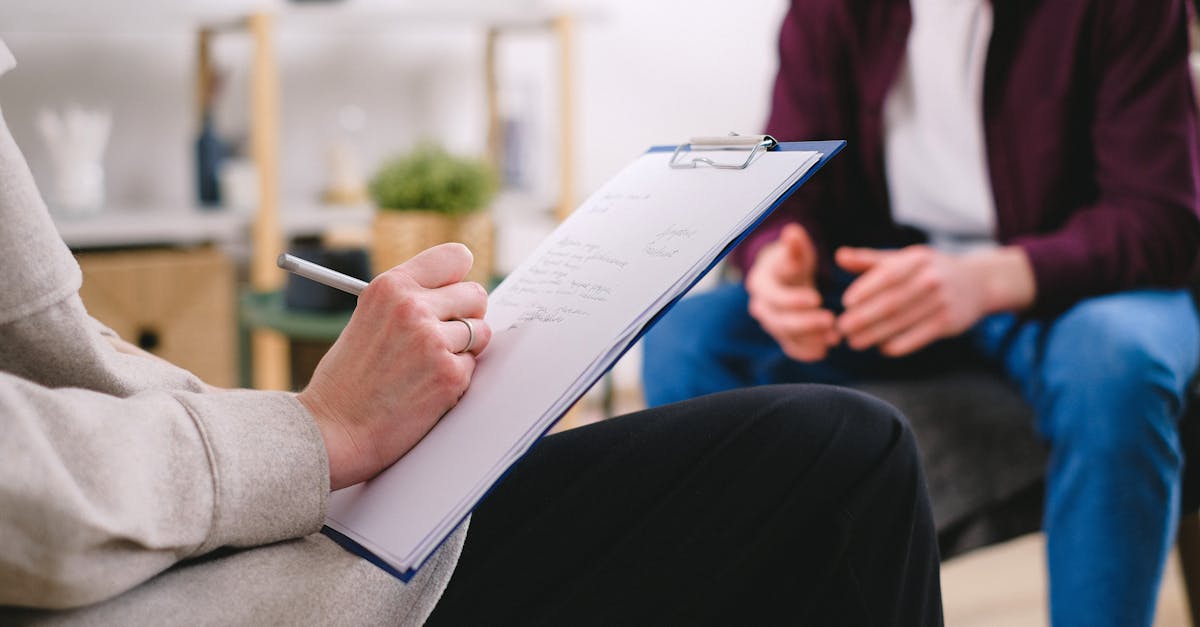 A smiling doctor discusses a digital health record on a tablet with a patient in a bright consultation room.