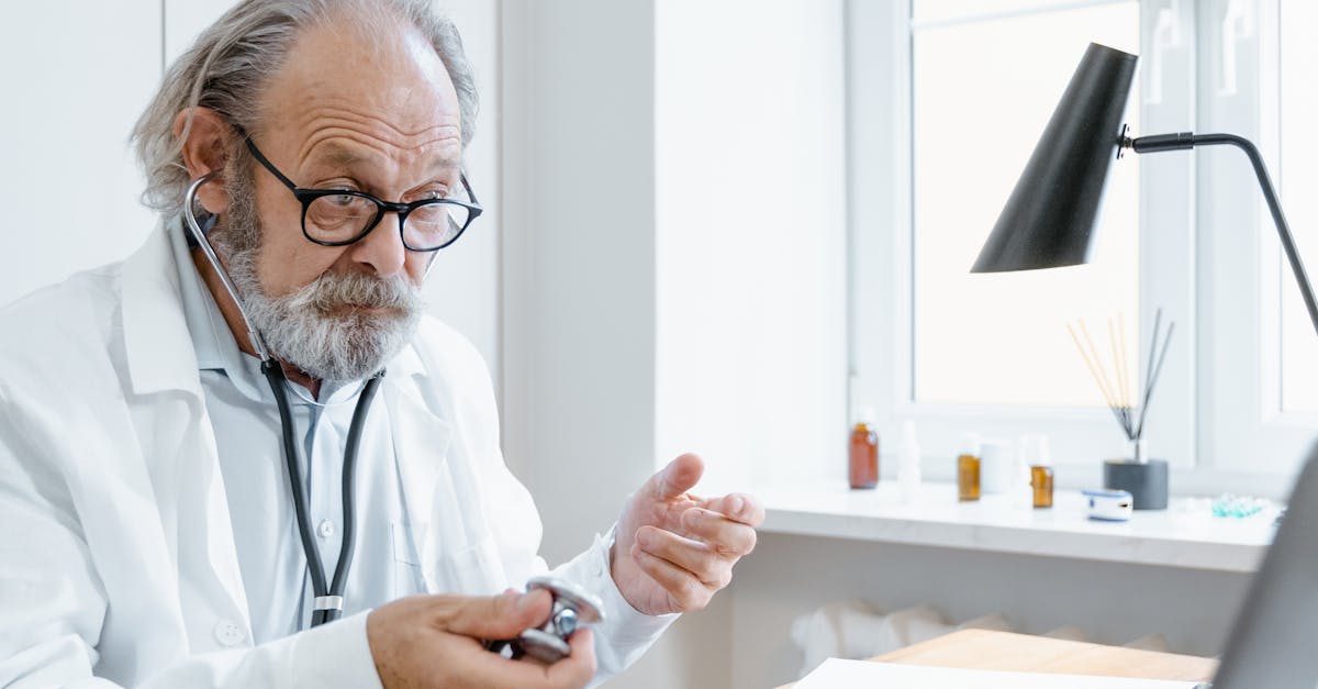 An elderly patient smiling during a telehealth consultation with their doctor on a laptop at home.