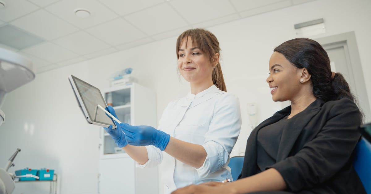 A female doctor in a modern clinic reviews a patient's electronic health record on a tablet.